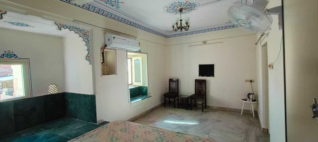 Traditional interior room with decorative ceiling design, marble flooring, wall seating, wooden chairs, and natural light